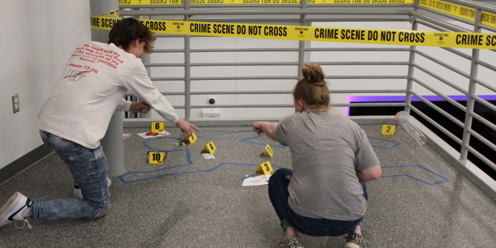 student examining fake crime scene