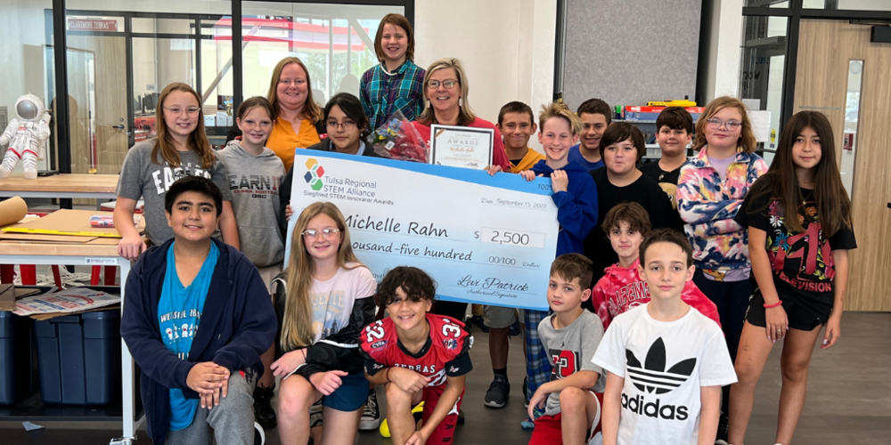 Mrs. Rahn with students, check, and Tulsa STEM Alliance representative with big check