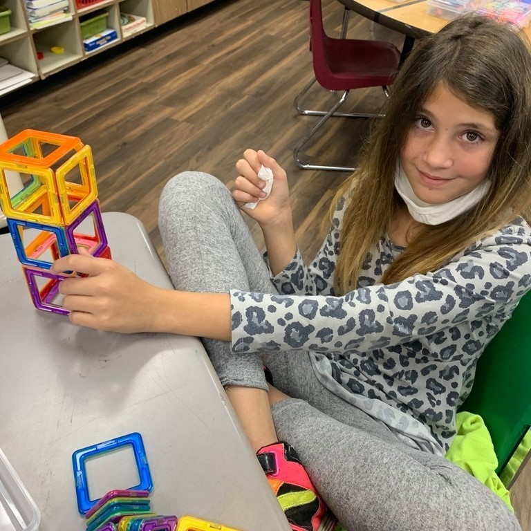 student using magnetics to build blocks