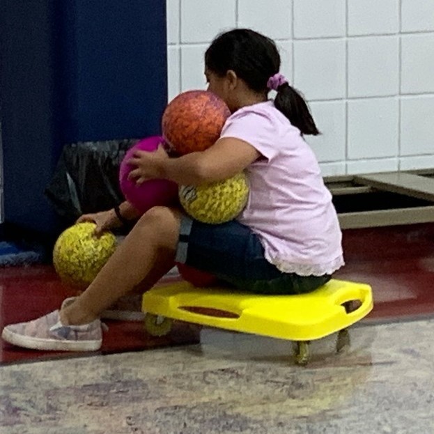 girl on scooter pick up balls