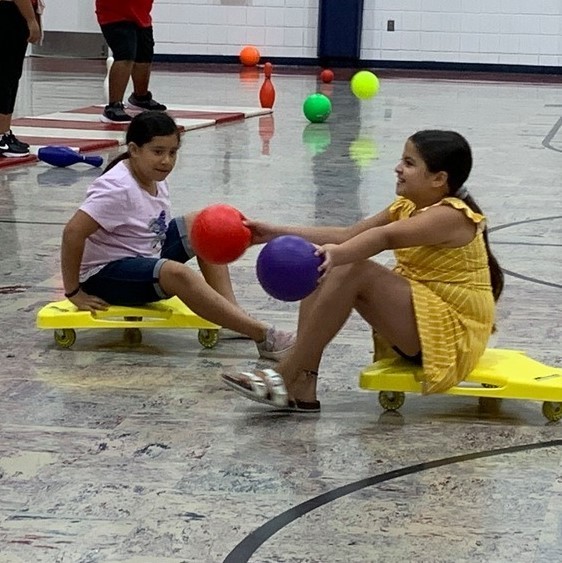 two girls on scooters with balls