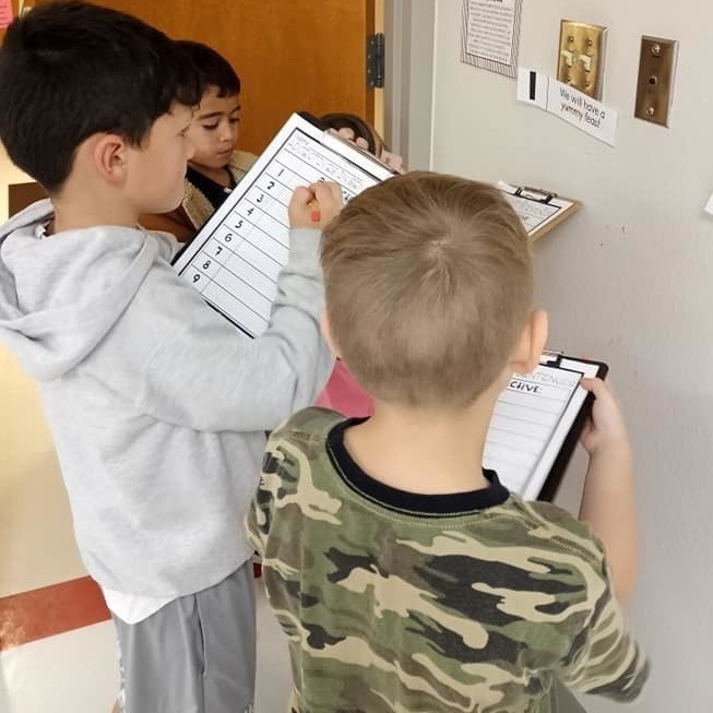 Students with a list of adjectives on a clipboard