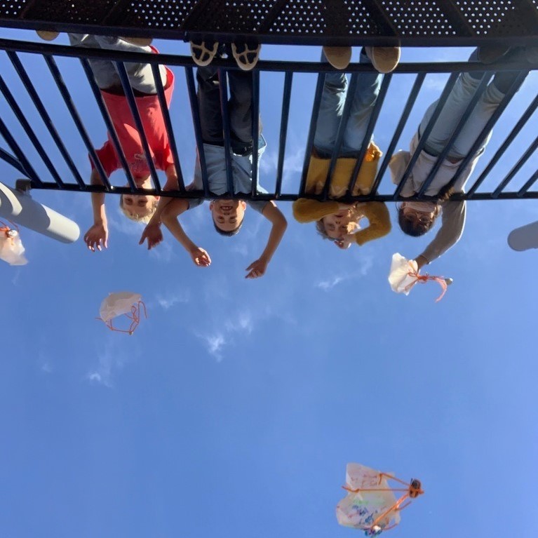 students dropping parachutes from the playground equipment
