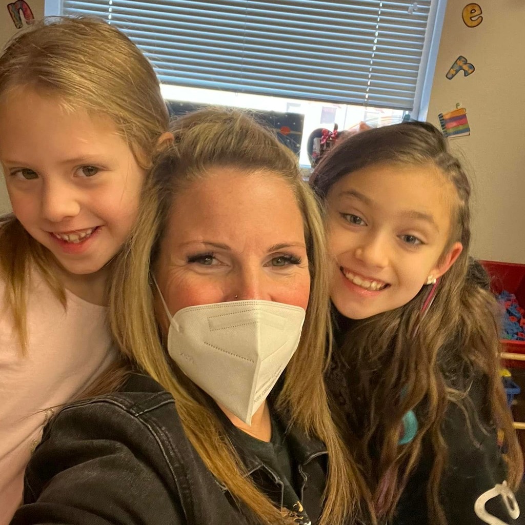 teacher in mask with two students over her shoulder 