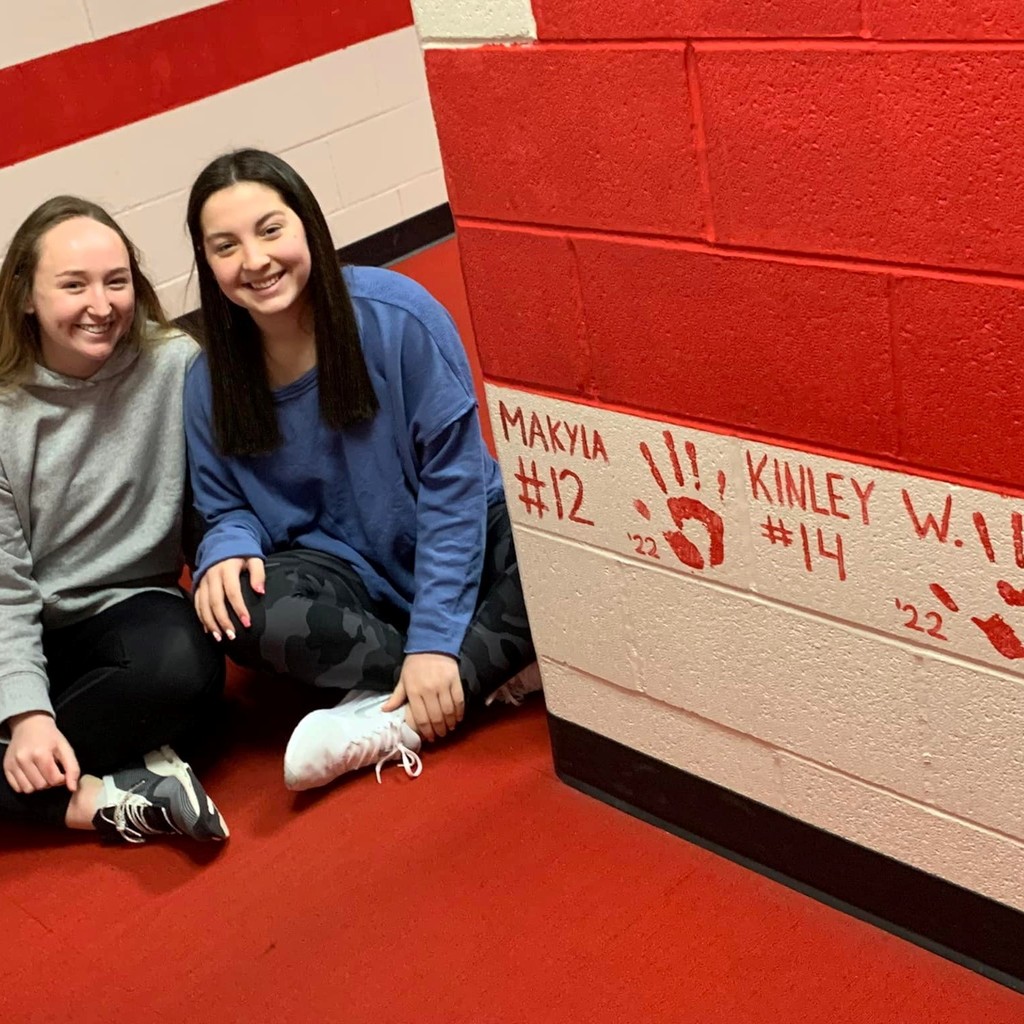 two players sitting beside handprints on the wall 