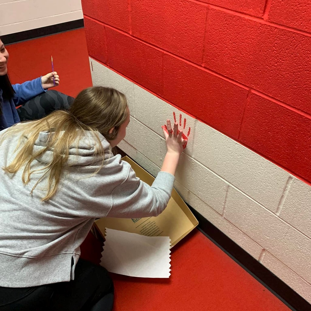 player paining her hand print on the wall 