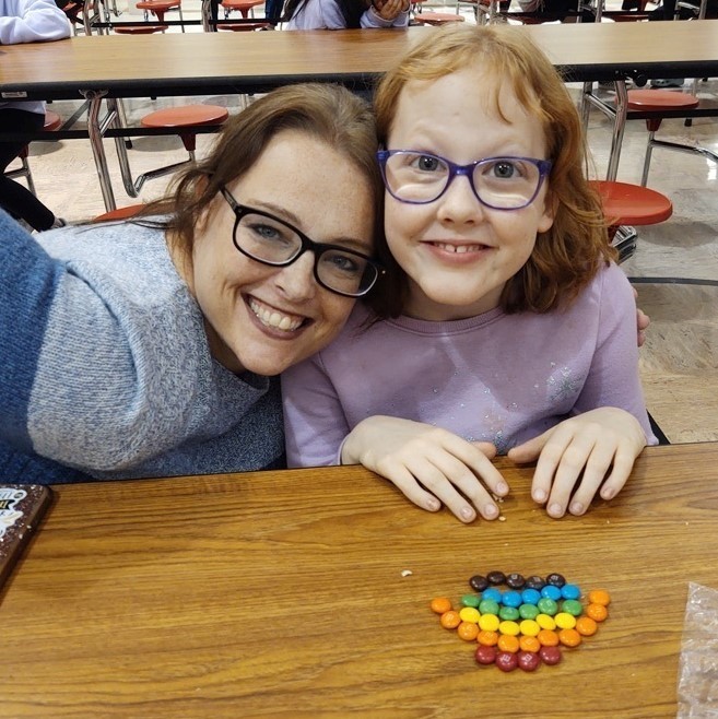 teacher with students smiling with a skittle rainbow 