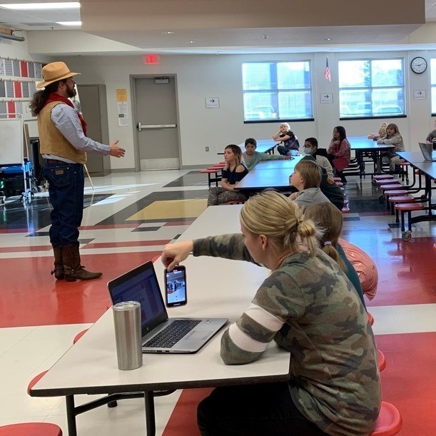 cowboy bart in front of students in cafeteria 