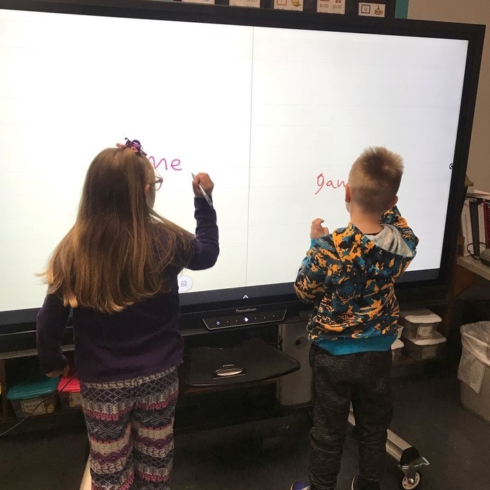 Students writing their names on the Promethean board
