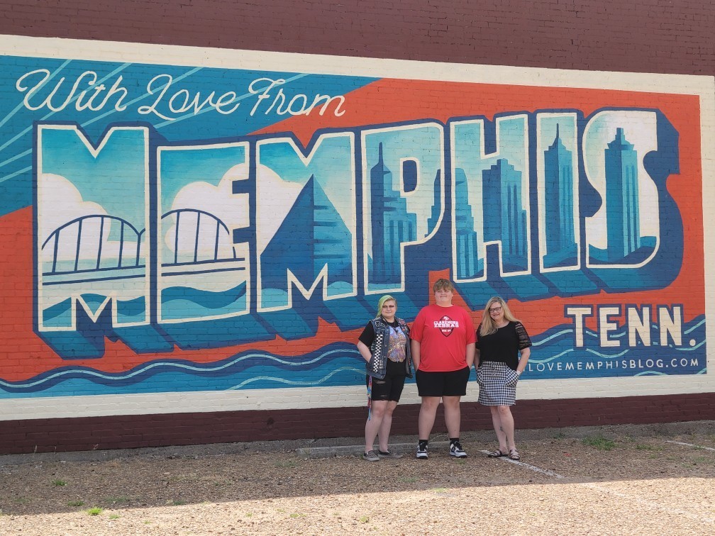 3 people in front of Memphis sign