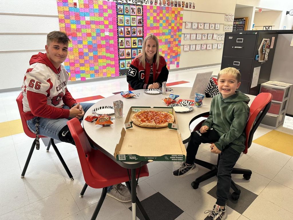 elementary student eating with football player and cheerleader 