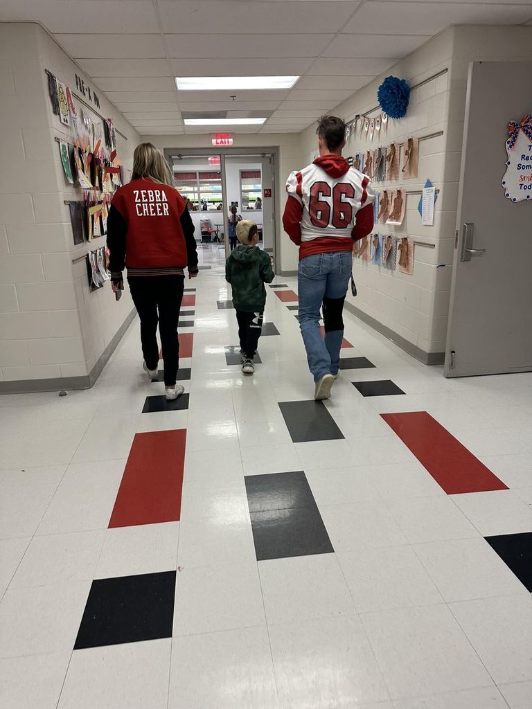 elementary student walking with football player and cheerleader 