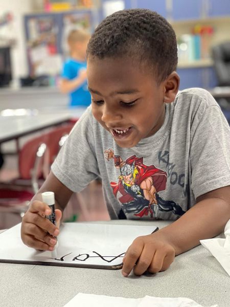 student writing letters on a whiteboard