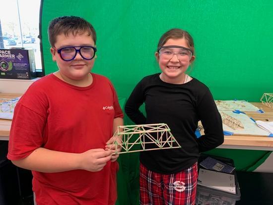 students holding bridge they built 