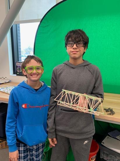 students holding bridge they built 