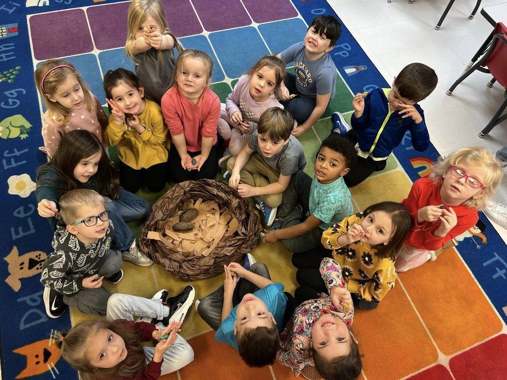 students gathered around fake dinosaur nest