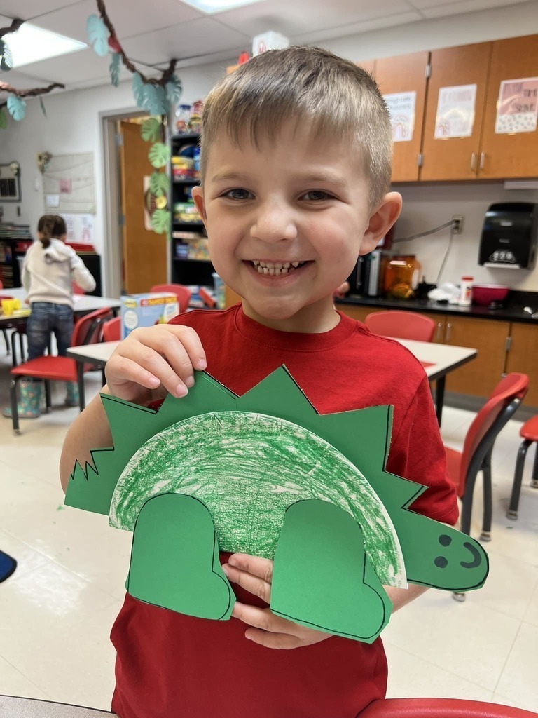 student holding paper dinosaur 