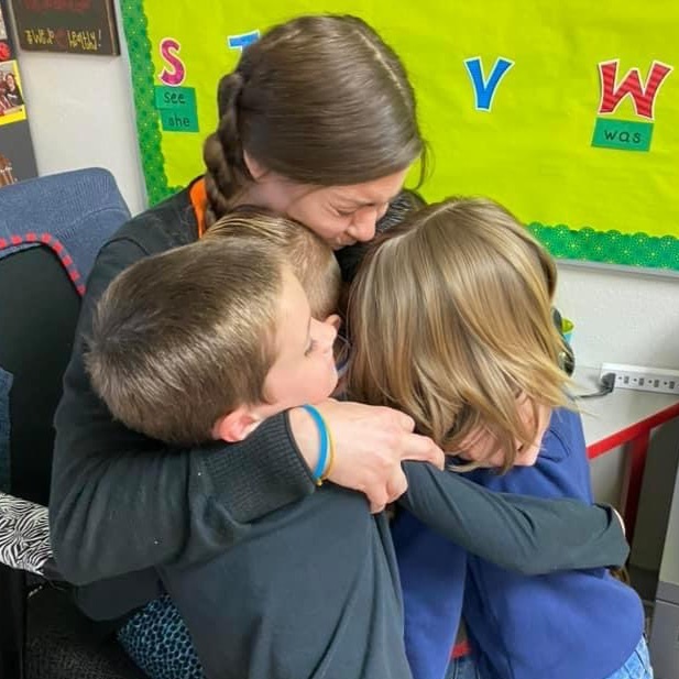 teacher, hugging students