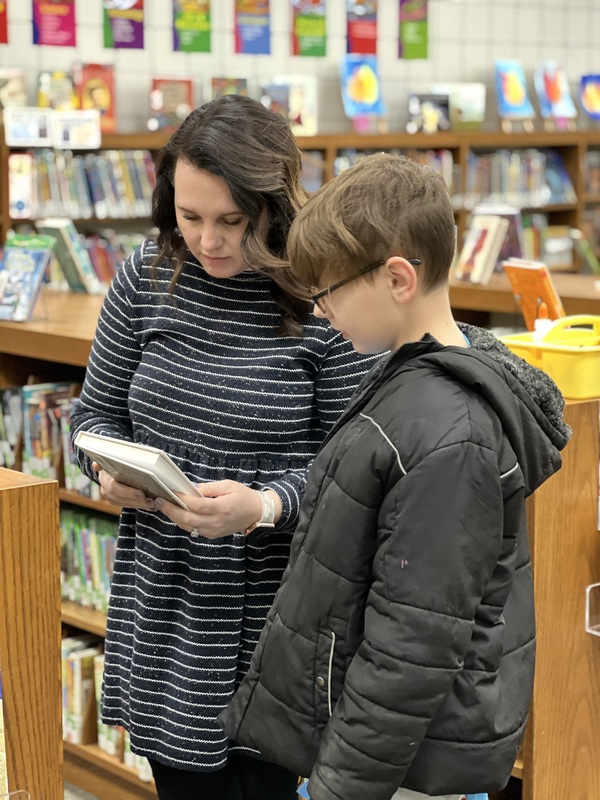 mrs troyer showing a student a book